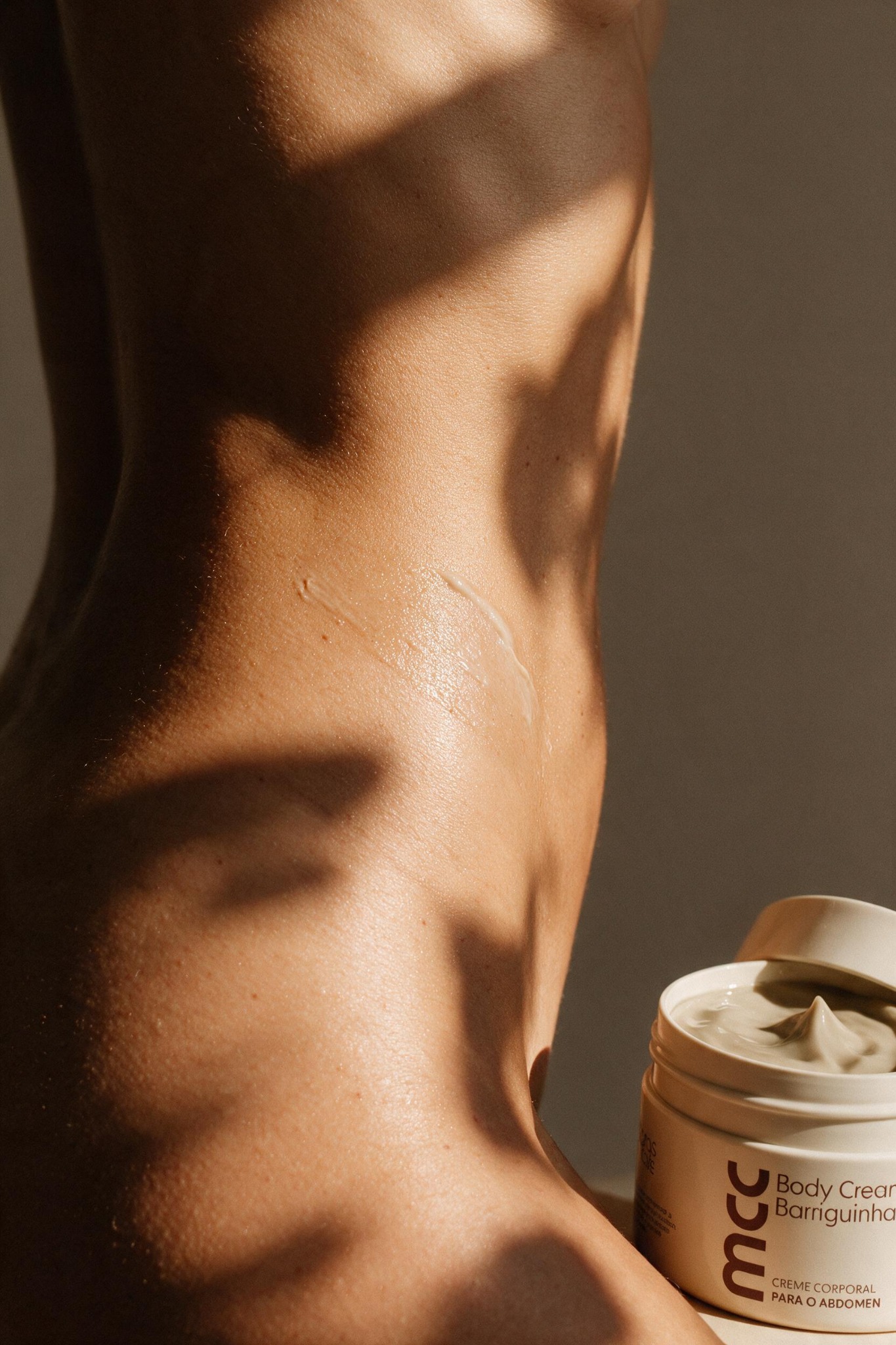 Close de pele real aquecida pela luz natural com o Body Cream aberto